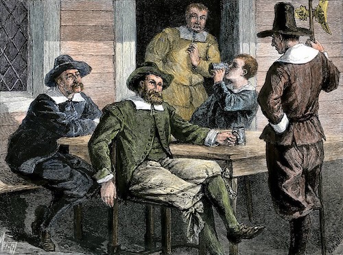 A colorful illustration depicts a group of Puritan men gathered around a wooden table. Some are seated, one is drinking from a pewter mug, and another stands to the right, all dressed in 17th-century attire.