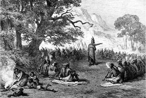 A black-and-white engraving depicts a historical scene of Pontiac, addressing a large group of warriors in an open clearing. Pontiac, wearing a feathered headdress, stands with one arm outstretched in a powerful gesture while the other men sit in a circle, listening intently, with an encampment and mountainous landscape in the background.