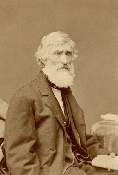 A sepia-toned photograph of Asher B. Durand, a 19th-century American painter of the Hudson River School. He is depicted in his later years, wearing a dark coat and vest, with a serious expression and a full, long white beard and hair.
