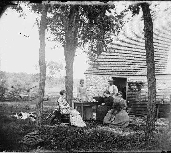  A black-and-white photograph captures a rural Southern family gathered outside a simple wooden house, representing the median household experience during the era of wealth compression. The modest setting reflects the 38% drop in wealth felt by average households as the economic gap between the middle class and the former elite narrowed.
