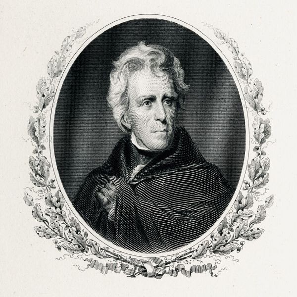 A finely detailed black-and-white engraving shows a portrait of Andrew Jackson, with his hair slightly disheveled and a serious expression on his face. The oval portrait is framed by an ornate wreath of oak leaves and a banner below, giving it a formal and distinguished appearance.